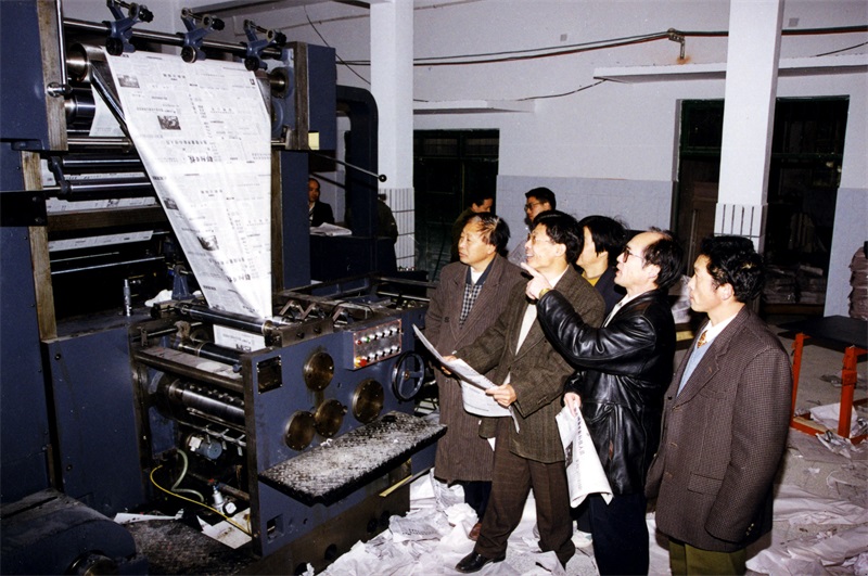 1998年2月，为了适应发行量日益扩大的需要，本报从北京购进一台全新胶印轮转机印刷大报。图为社领导在察看印刷机试运行情况。